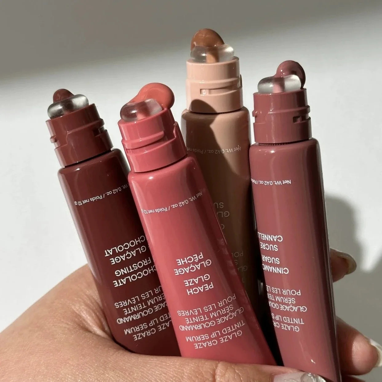 MAIRA'S COLLECTIONS Donut Lip Oil with strawberry, raspberry, and chocolate scents, showing a cute donut-shaped lip balm in a clear container.